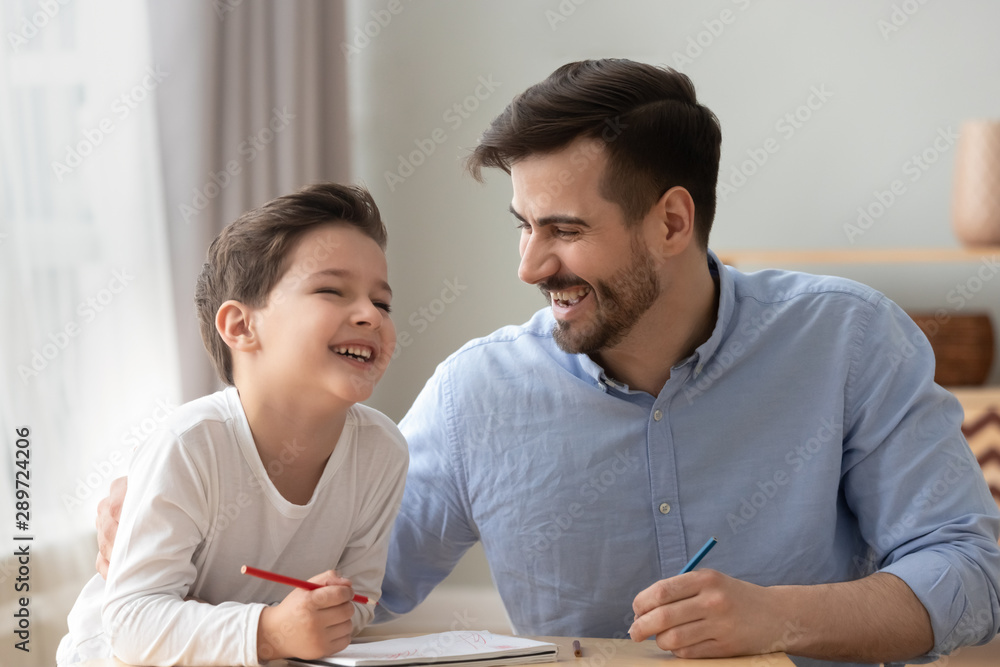 Happy dad and little kid son laughing drawing together Happy dad and little kid son laughing drawing together