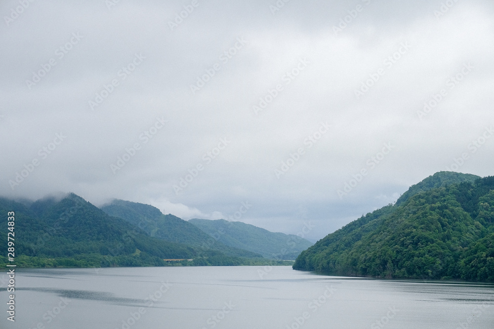 mountain view and misty covering over the river in morning with overcast sky at Hokkaido, Japan.. mountain view and misty covering over the river in morning with overcast sky at Hokkaido, Japan..