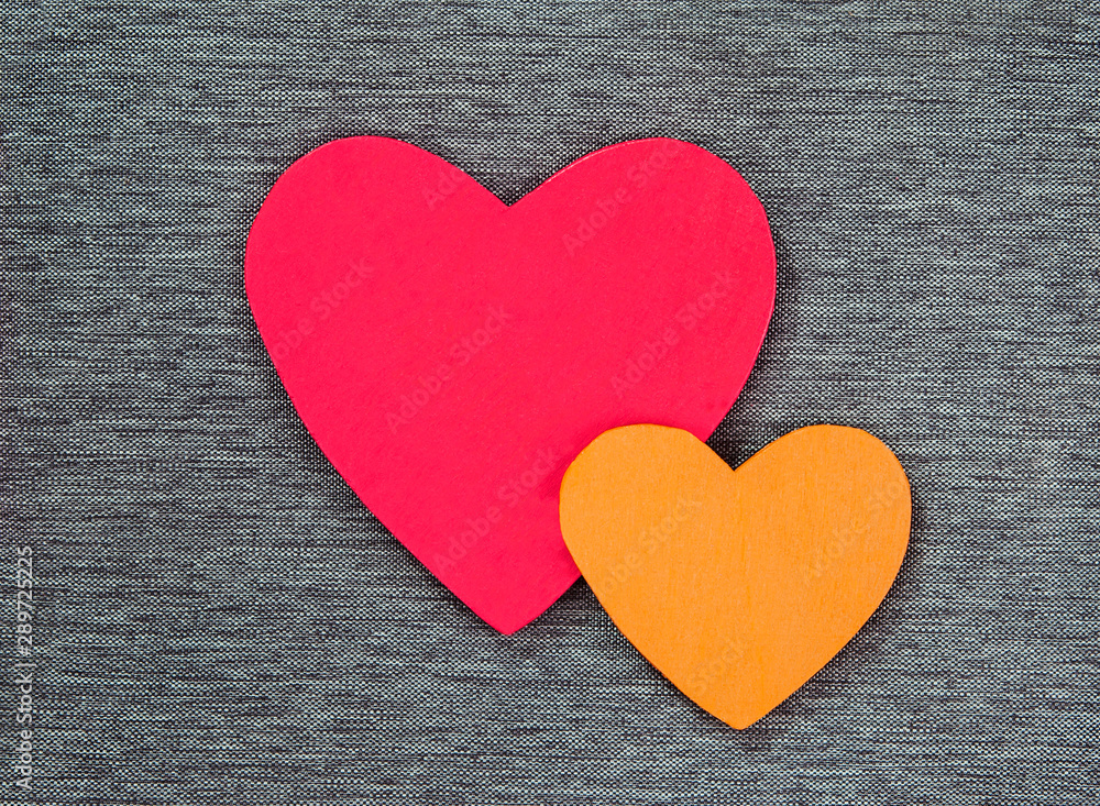 Wooden heart shapes on gray material, in red & gold - concepts of love, good feelings or Valentines, as a background texture with design space. Wooden heart shapes on gray material, in red & gold - concepts of love, good feelings or Valentines, as a background texture with design space.