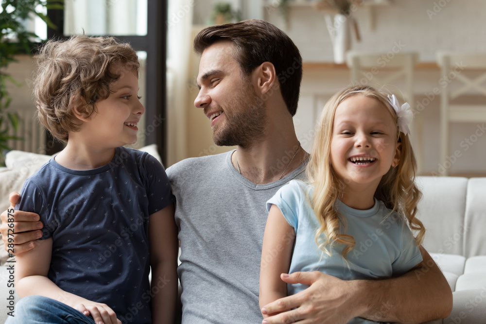 Happy young single daddy hugging two small children. Happy young single daddy hugging two small children.