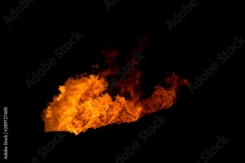 One flame stack at night. This is the flare stack at a refinery. All that is visible is the flame on a black background. Flame blown by the wind. © madscinbca