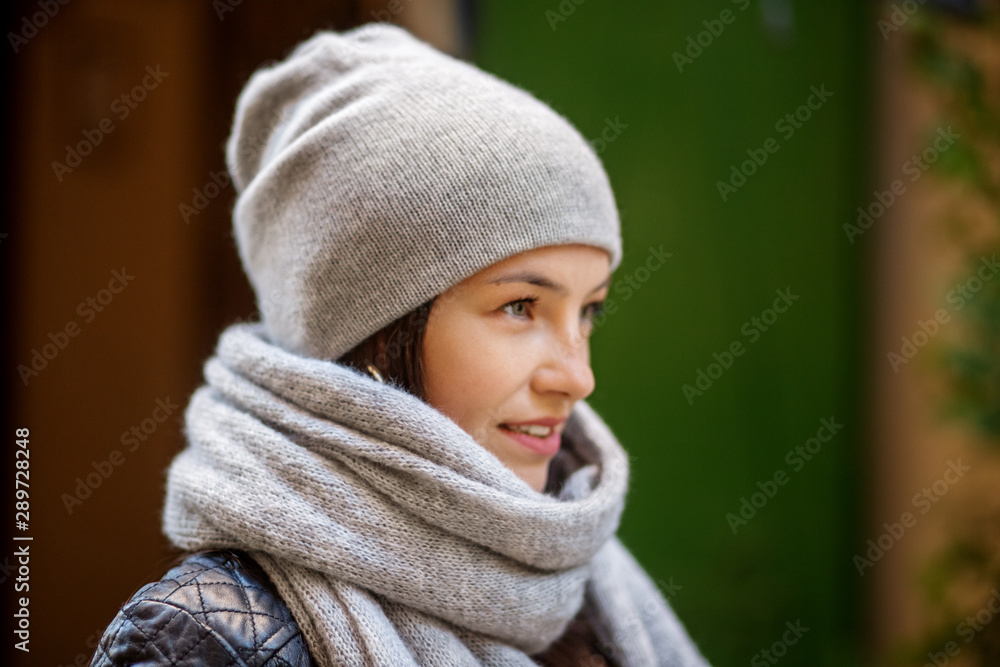 Beautiful woman in a gray knitted hat and scarf. Concept lifestyle, autumn, urban Beautiful woman in a gray knitted hat and scarf. Concept lifestyle, autumn, urban
