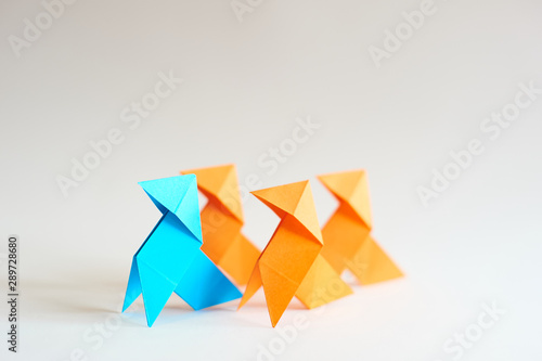Photograph of a blue paper bow tie  followed by three orange paper bow ties  with a white background. Space for text. Ideal for presentations. For background.
