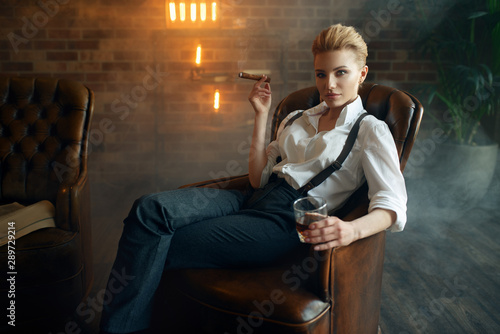 Woman sitting in chair with whiskey and cigar photo