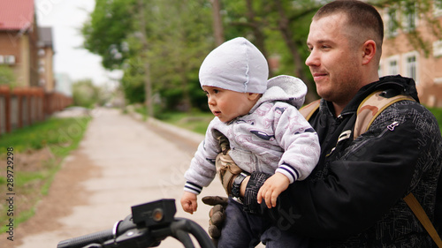 Smiling adult men holding cute little baby on his arms