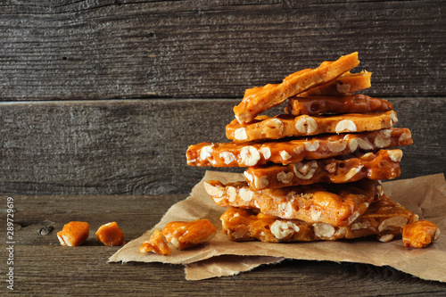 Stack of traditional peanut brittle candy pieces against a rustic wood background photo