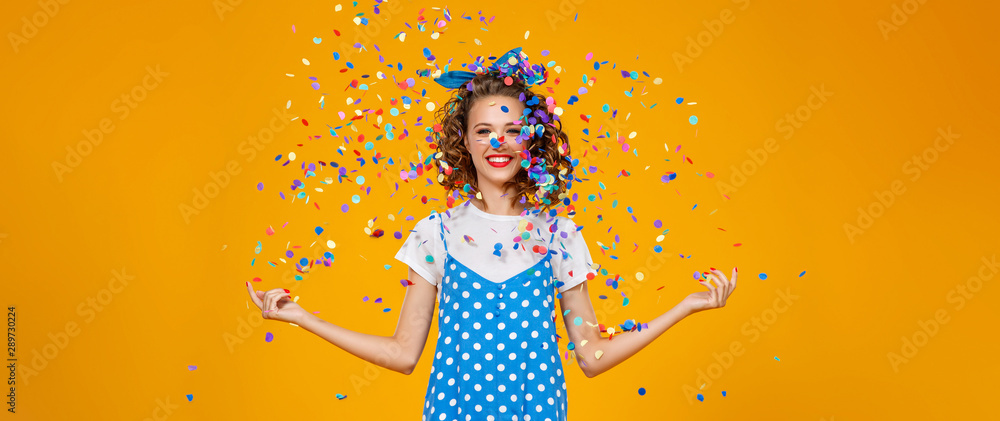 cheerful funny young woman with festive confetti on yellow . - obrazy, fototapety, plakaty 