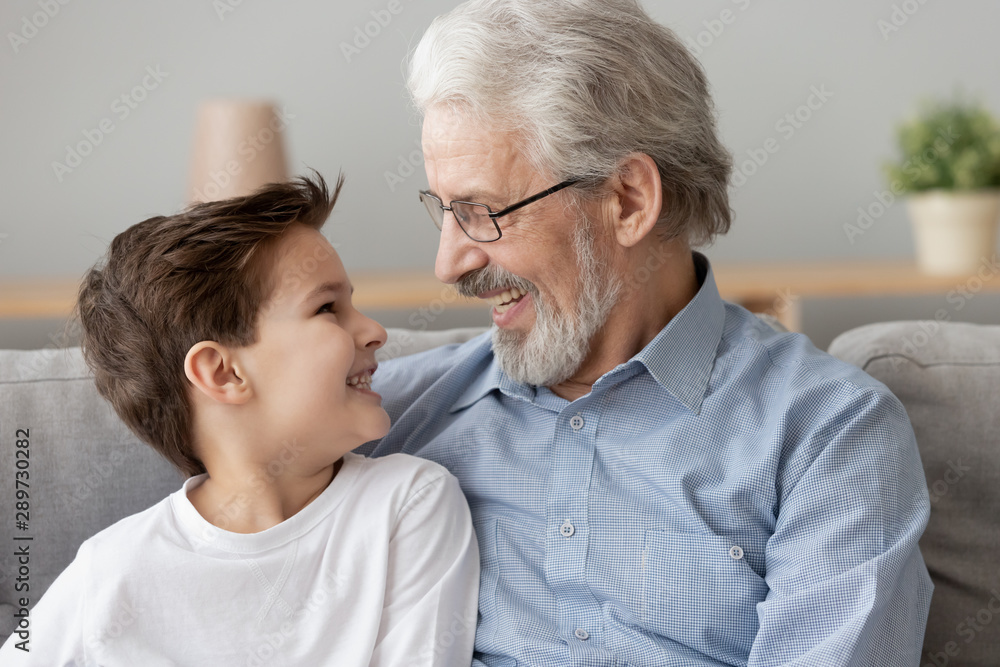 Smiling senior old grandfather embrace little boy grandson at home Smiling senior old grandfather embrace little boy grandson at home
