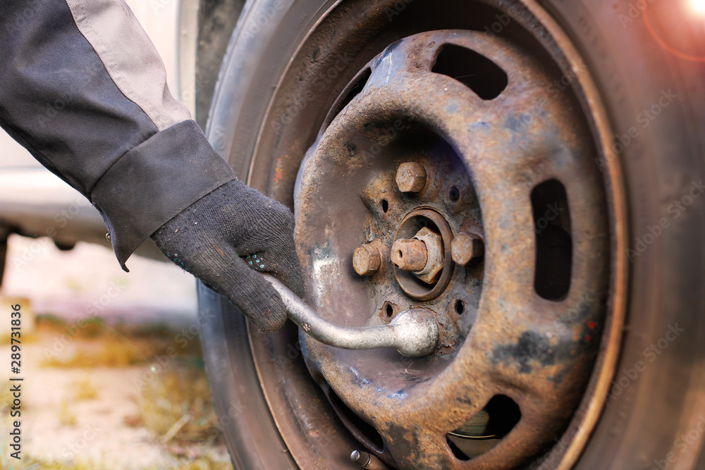 replacing a wheel in a car, loosening nuts with a hand wrench. replacing a wheel in a car, loosening nuts with a hand wrench.
