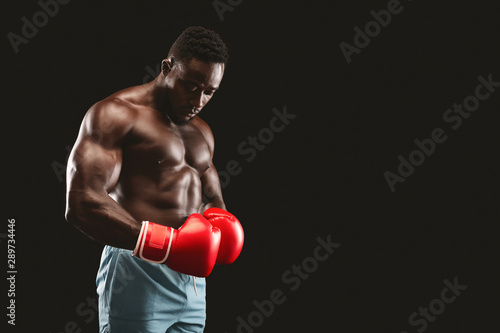 African fighter with red gloves on posing over black background © Prostock-studio