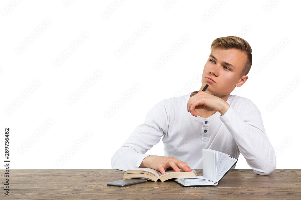 young guy sitting at the table with books and thinking young guy sitting at the table with books and thinking