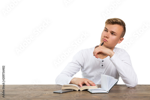 young guy sitting at the table with books and thinking