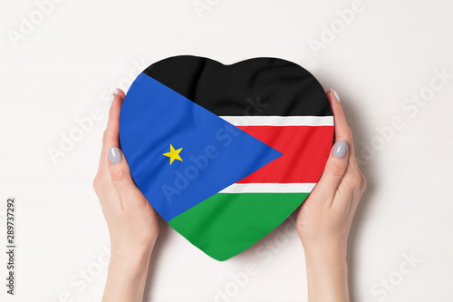 Flag of South Sudan on a heart shaped box in a female hands. White background
