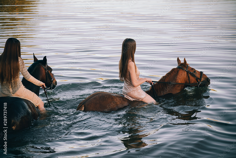 Two girls riding horses in the river