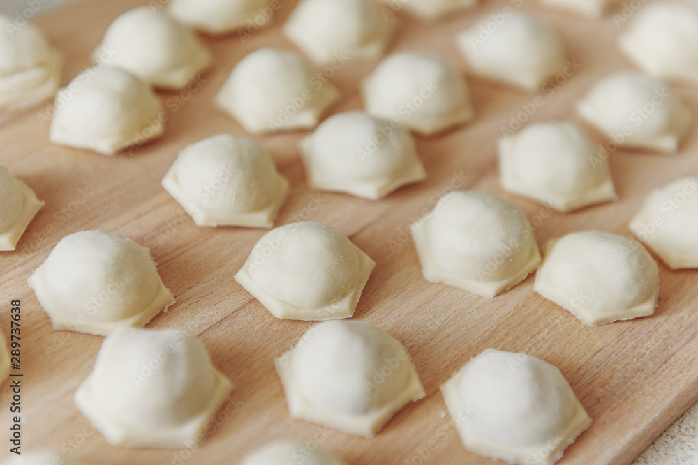 Dumplings with minced meat sculpts cook in the kitchen. Prepare homemade dumplings on the table, sprinkled with flour. Homemade meat dumplings. Sculpt dumplings. Dumplings with minced meat sculpts cook in the kitchen. Prepare homemade dumplings on the table, sprinkled with flour. Homemade meat dumplings. Sculpt dumplings.