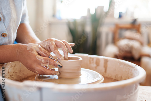 Fotografia, Obraz Female potter making a pot on pottery wheel