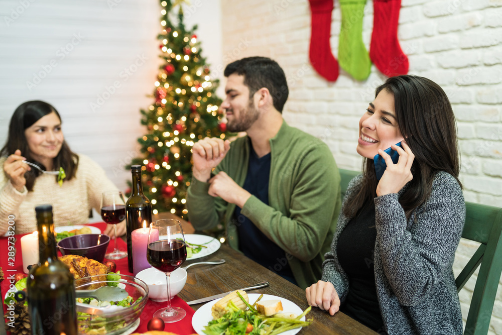 Smiling Woman Giving Merry Christmas Wishes On Mobile Phone At Home Smiling Woman Giving Merry Christmas Wishes On Mobile Phone At Home