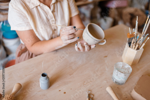Female master paints a pot, pottery workshop