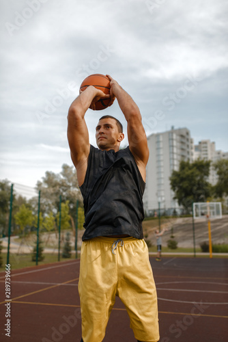 Basketball player makes a throw on outdoor court