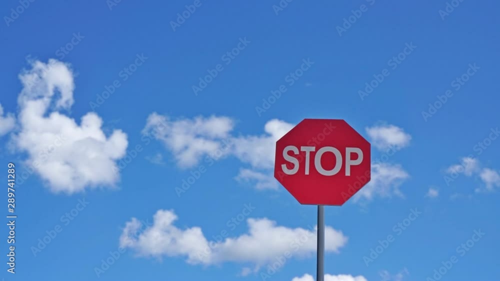 Red stop sign on a background of blue sky with clouds. Time-lapse Red stop sign on a background of blue sky with clouds. Time-lapse