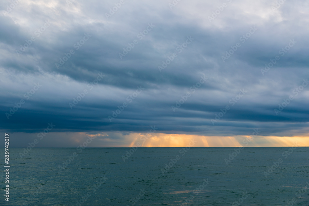 Vivid sunset over the Black Sea with rainy clouds