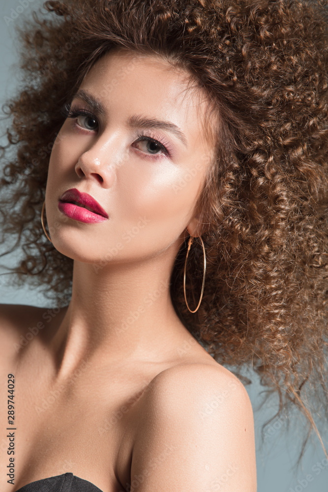 portrait of curly woman on a blue background. Hairstyle and makeup portrait of curly woman on a blue background. Hairstyle and makeup
