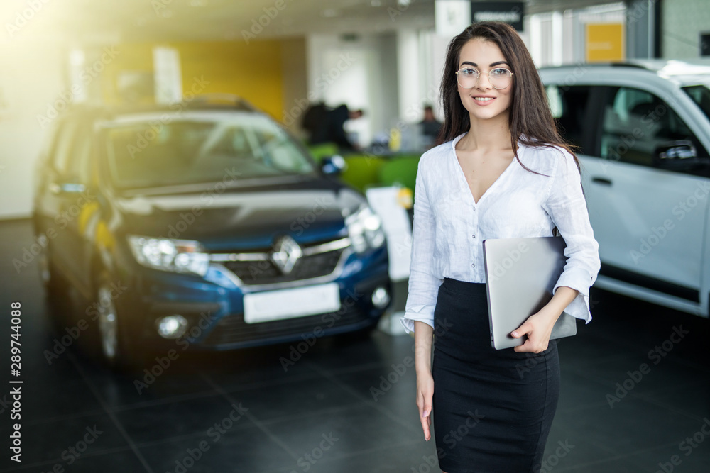 Young woman with laptop in car salon