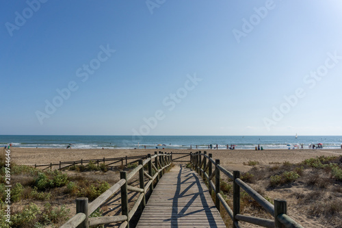 Wooden bridge in a surfing beach with dunes and vegetation