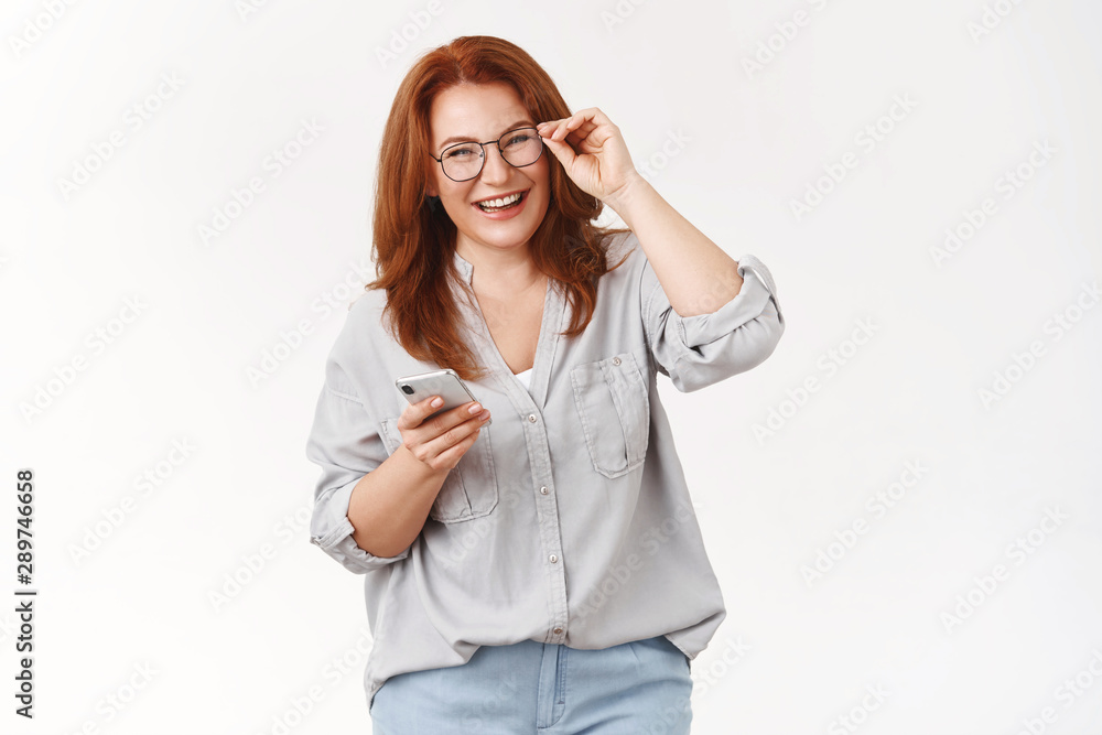 Never was easier. Cheerful carefree happy emotive redhead middle-aged woman checking glasses hold smartphone laughing pleased joyful camera get used new phone managing schedule via cellphone Never was easier. Cheerful carefree happy emotive redhead middle-aged woman checking glasses hold smartphone laughing pleased joyful camera get used new phone managing schedule via cellphone