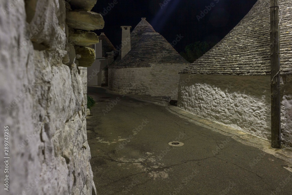 Obraz premium ALBEROBELLO, ITALY - AIGUST 28 2017: Night view of an alley in Alberobello, south of Italy