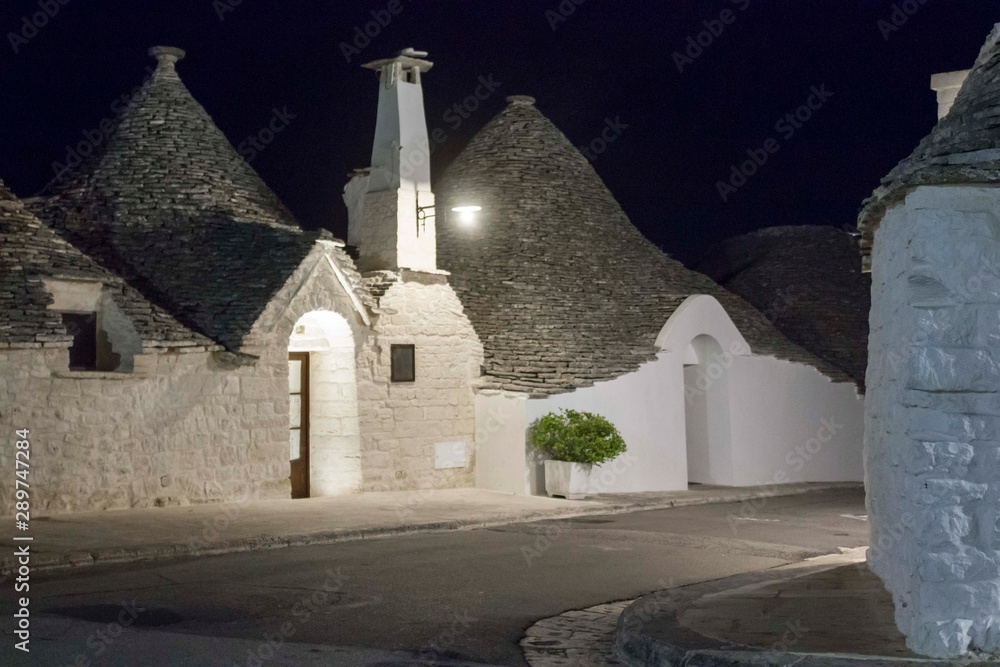 ALBEROBELLO, ITALY - AUGUST 27 2017: Night view of a traditional narrow street in Alberobello, with its famous construction names trulli