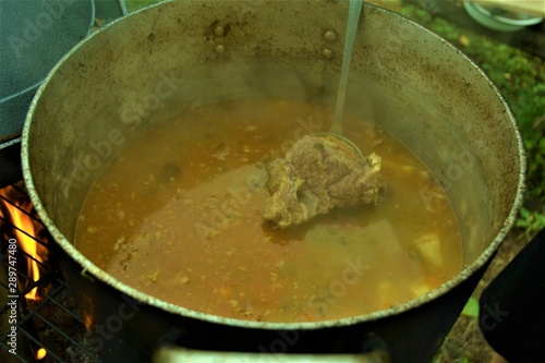 yellow soup with meat cooked over an open fire
