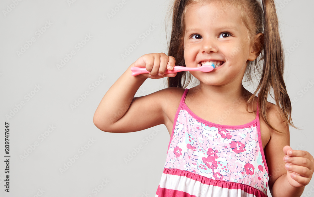 Little girl brushing teeth with toothbrush over white background with copy space Little girl brushing teeth with toothbrush over white background with copy space