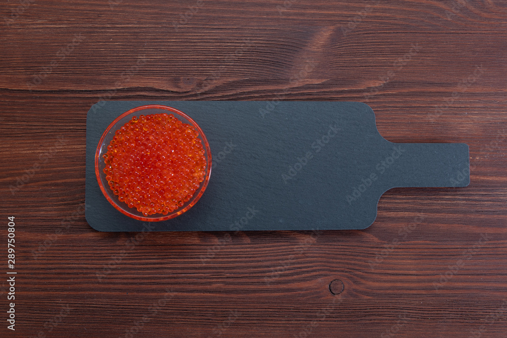 Red caviar in the glass jar on the grey stone background Red caviar in the glass jar on the grey stone background