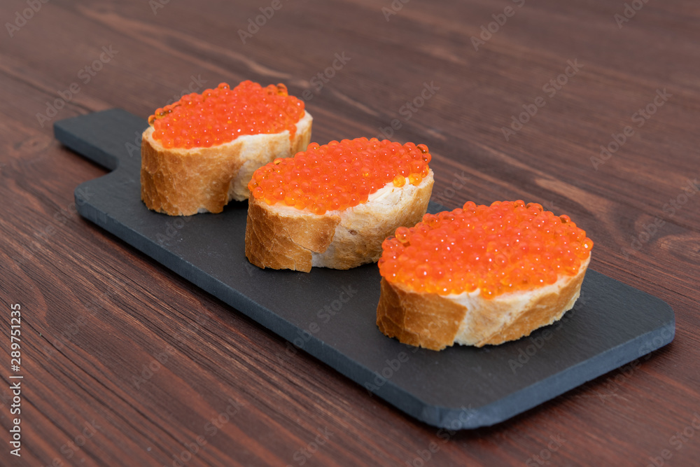 Set of three sandwiches with red caviar on the grey stone background Set of three sandwiches with red caviar on the grey stone background