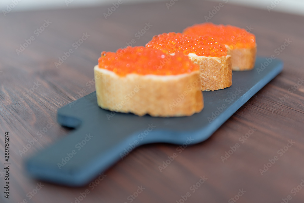 Set of three sandwiches with red caviar on the grey stone background Set of three sandwiches with red caviar on the grey stone background