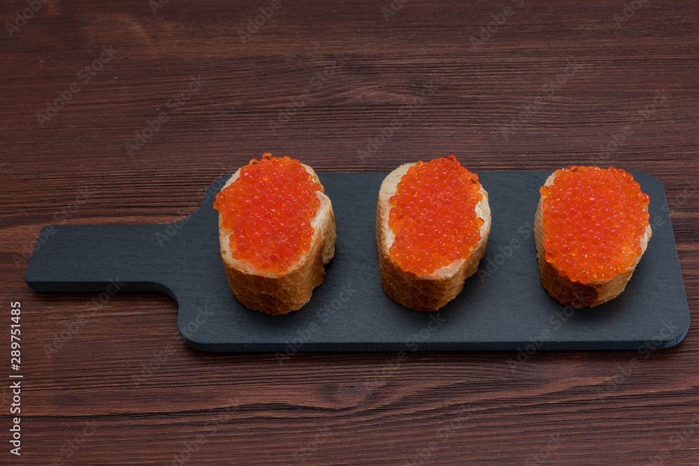 Set of three sandwiches with red caviar on the grey stone background Set of three sandwiches with red caviar on the grey stone background