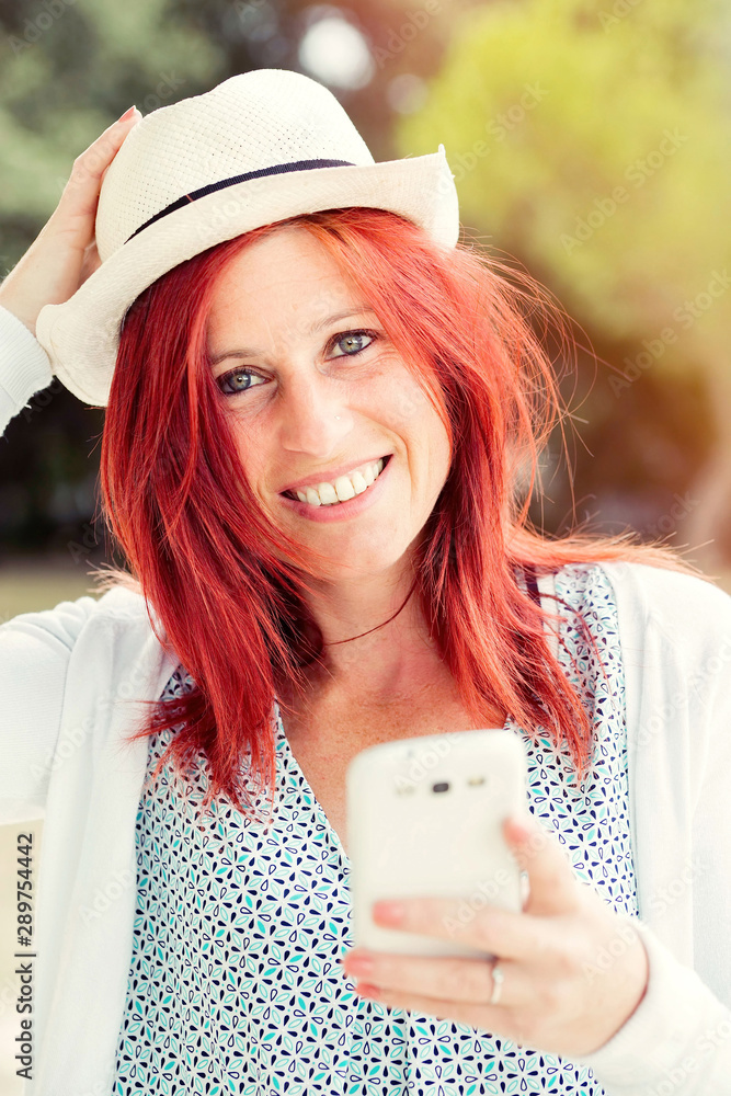 Smiling beautiful young woman close up with mobile phone, against background of summer green park. Smiling beautiful young woman close up with mobile phone, against background of summer green park.