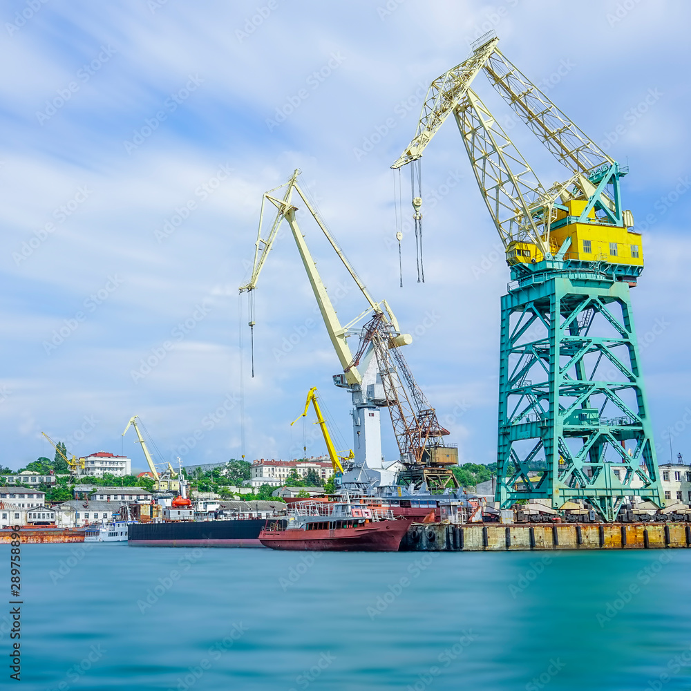 Seascape with the coastline of the port and large floating cranes.