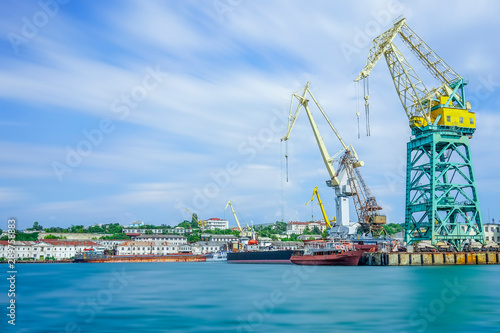 Seascape with the coastline of the port and large floating cranes.
