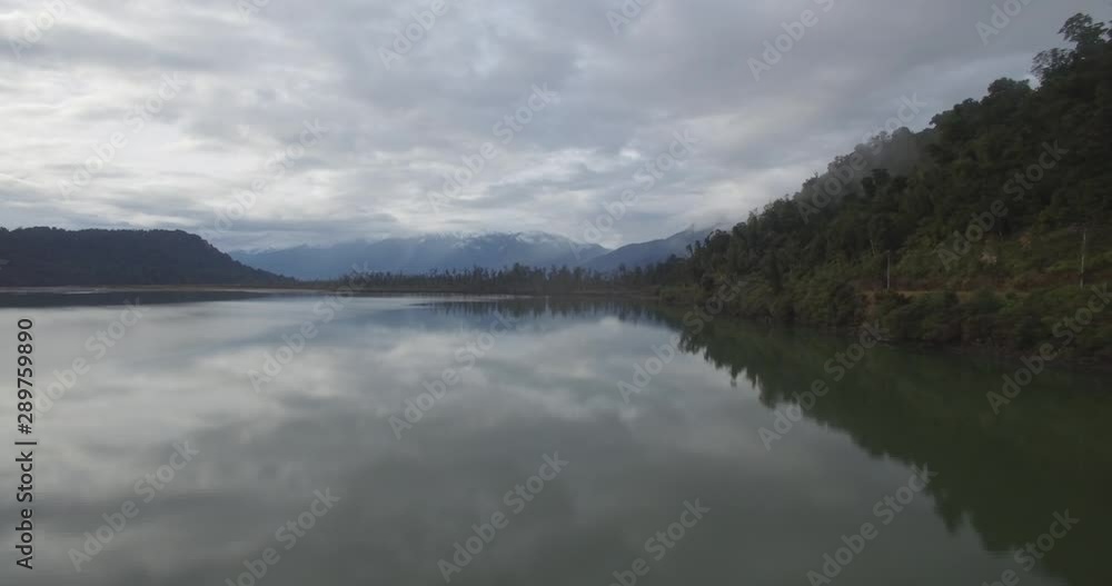 Aerial of Intact Lake Under Mountainous Hills And Cloudy Skyline. New Zealand West Coast Nature Aerial of Intact Lake Under Mountainous Hills And Cloudy Skyline. New Zealand West Coast Nature