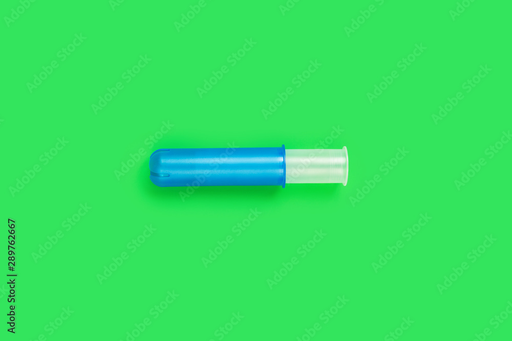 Empty blue plastic tampon applicator isolated on bright neon green background Empty blue plastic tampon applicator isolated on bright neon green background