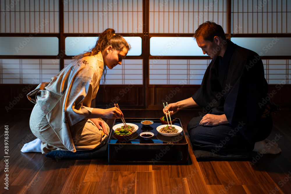 Young couple seiza sitting on floor pillows with Japanese ryokan