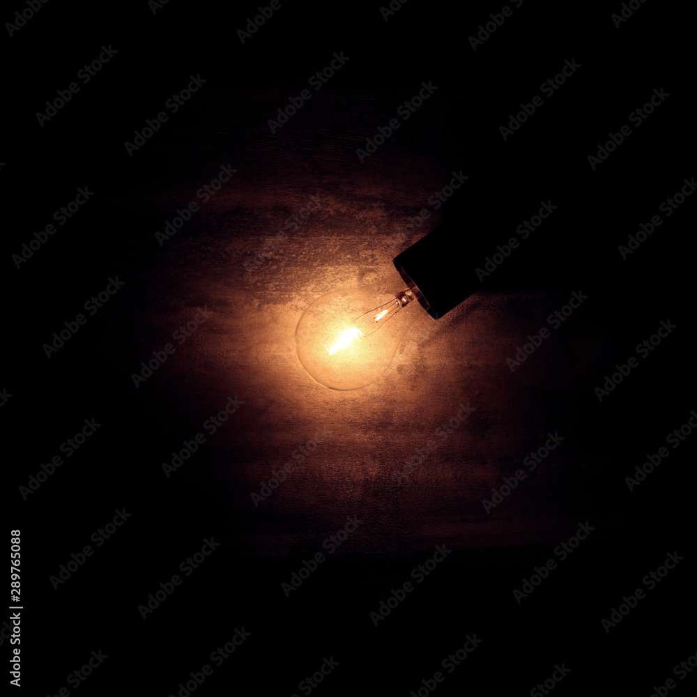 Vintage old light bulb dimly lit on rough dark background. Idea