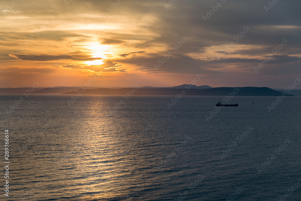 Beautiful sunset view over the sea and ship silhouette