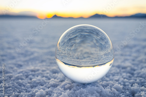 Ground level closeup view on crystal ball with reflection of Bonneville salt flats  mountains at colorful sunset