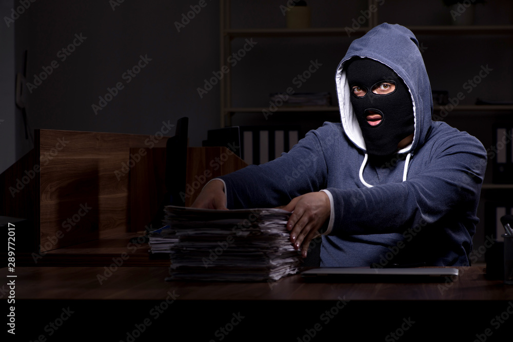Male thief in balaclava in the office night time Male thief in balaclava in the office night time
