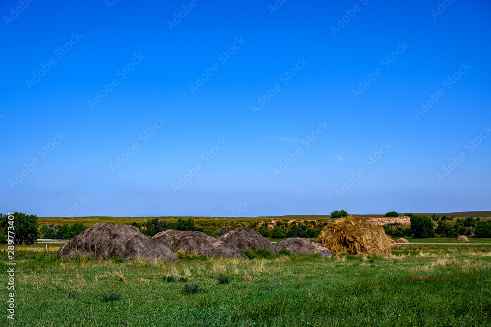 Obraz premium Hay stack on grass field on sloped hillside