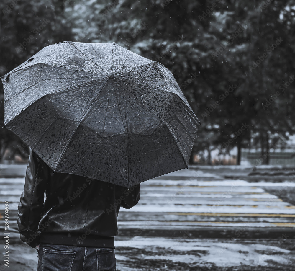 man with umbrella in rain. abstract background. focus on man and umbrella.  man with umbrella stands