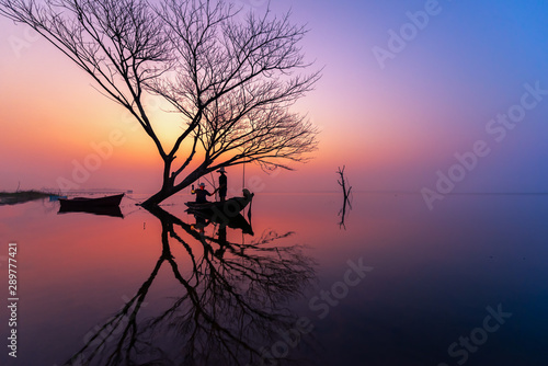 Silhouette of Myanmar fisherman on wooden boat .